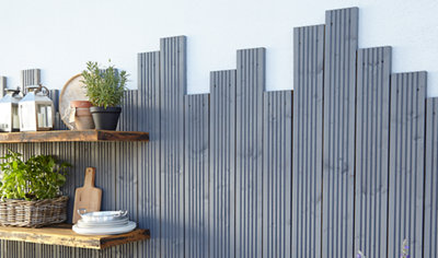 Grey decking boards attached to a white exterior wall in varying heights to create a stylish feature.