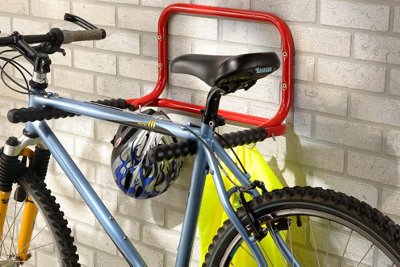 A bicycle stored on a bike holder attached to a brick wall.