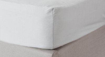 Close-up of the corner of a bed sheet neatly placed over a mattress.