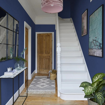 A dark hallway painted in Valspar Deep Ocean Floor with wall art and staircase 