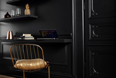 Black room with wall mounted narrow desk and gold effect chair.