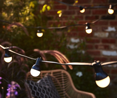 Festoon lights with bulbs hanging from a wire spaced evenly apart, creating a charming and atmospheric lighting setup in a garden patio.