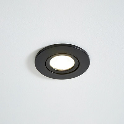 A black kitchen downlight featuring a black circular frame with a bulb in the centre.