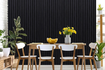 Feature wall with vertical black panelling behind a dining table with dining chairs.