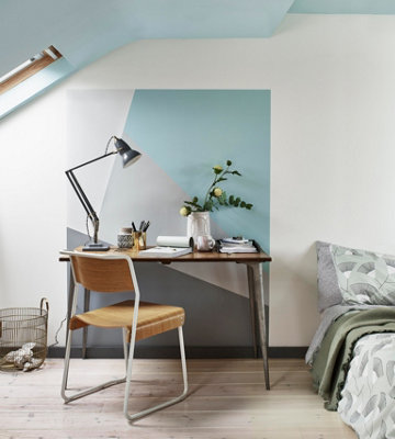 A home office with a vibrant blue and grey geometric feature wall.