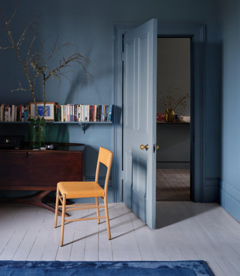 A stylish room fully painted in a single shade of blue, including the walls, door, trims, and shelving, creating a striking and cohesive look.