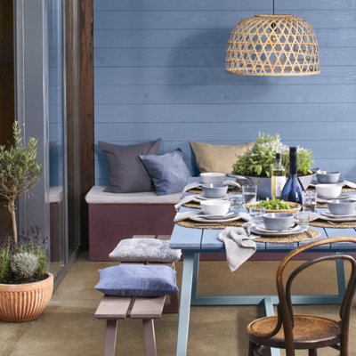A small garden with a blue exterior wall and a blue dining table set for dinner.