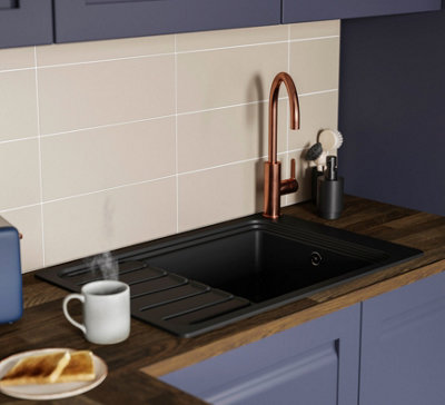 A blue kitchen with a black single bowl sink and rose gold tap.