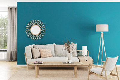 A blue living room, that has a white sofa with a lamp to the right of it, and a coffee table in front of the sofa.