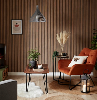 A boho living room with wall panel wallpaper and a burnt orange upholstered armchair.