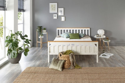A white wooden bed with a slatted headboard, in a modern grey bedroom space.