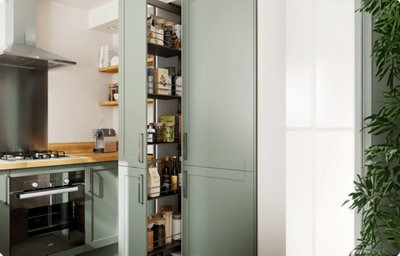 A tall shaker style kitchen cabinet is partially open to reveal various foods. The cabinet front is pale green and reveals a pull-out larder style cupboard, meaning the cupboard shelving pulls out into your kitchen for easy access to the contents.