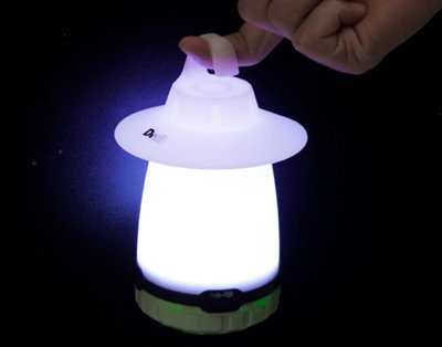 A small Diall camping lantern. Person is holding the camping lantern by a hook at the top.