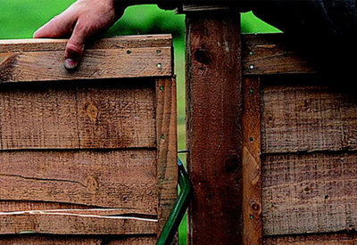Using a crowbar to lever one fence panel away from another to create a gap between them.
