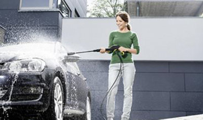 Person using a pressure washer to clean a car windscreen.
