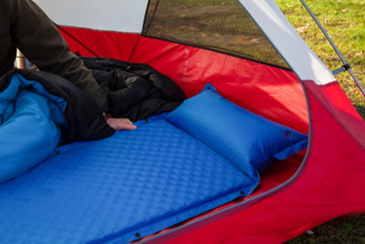 A camping mat laid flat inside a tent with a pillow above it.