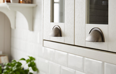 Close-up of ivory glass-fronted shaker kitchen cabinets with chrome handles