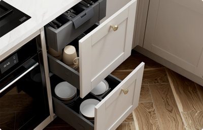 Two deep shaker-style kitchen drawers in light grey are open to reveal clever storage options. The bottom drawer has dividers for organising bowls or pots. The top drawer front houses two drawers - at the bottom a drawer deep enough for mugs, and a top drawer with a pull tab that houses cutlery.
