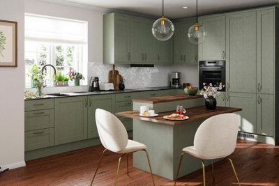 A large kitchen with sage green cabinets, dark wooden flooring, white walls and a white tiled splashback.