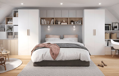 Spacious white bedroom with custom Atomia modular wardrobes flanking a double bed, and wall-mounted cube storage and shelves above the headboard.