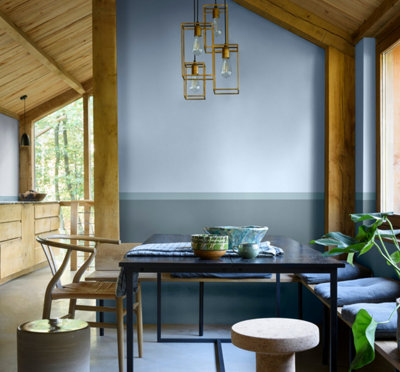 A dining area with a blue feature wall using three distinct shades of blue, complemented by matching blue cushions, tableware, and accessories.