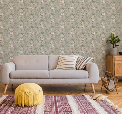 A living room with green floral wallpaper, a grey sofa with hairpin legs, a tasselled yellow pouffe and a red and white geometric boho rug.