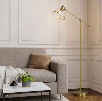 A cream wall panelled living room with a light brown sofa, gold floor lamp and marble coffee table.