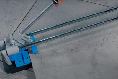 Person holding the handle of a manual tile cutter which has scored a line across a tile.