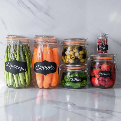 A selection of glass jars filled with a fruits and vegetables, with black labels showing detailing what is inside the jars.