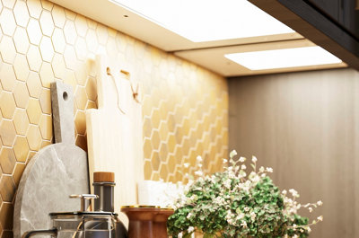 Under cabinet lights illuminating a gold effect hexagon mosaic tiled splashback.