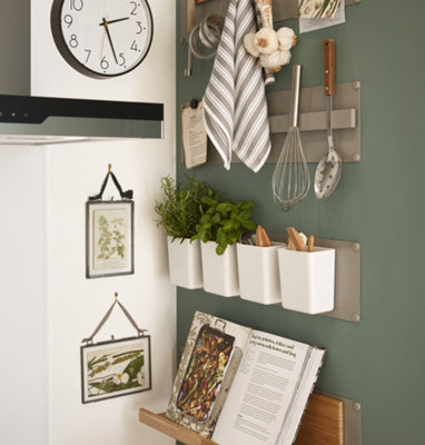 Green and white kitchen with magnetic wall panels for storage.
