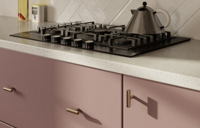 A close up pf the Ethos kitchen, featuring sleek soft pink cabinets, chrome fixtures and cupboard handles, and white marble countertops.