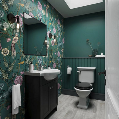 Dark green, colour drenched cloakroom bathroom with floral wallpaper and panelling 