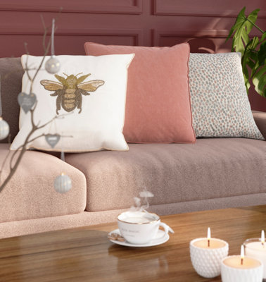 A dark pink living room with a selection of cushions on pink sofa.