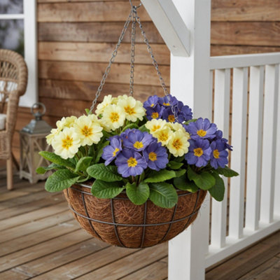 A hanging basket with purple and yellow flowers hanging above decking.