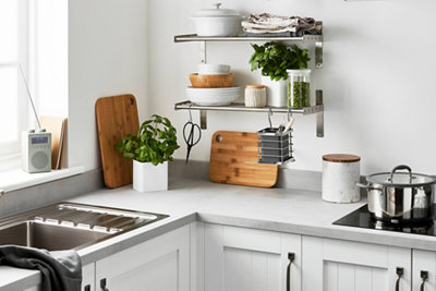 A modern kitchen space featuring two wall-mounted open shelves with neatly stacked bowls and pots on top, and various items hanging from the bottom.