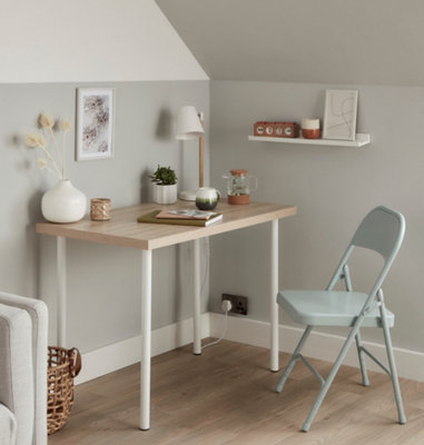 Light grey home office with a light wooden desk with white legs and a pale blue metal foldable chair.