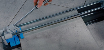 Person holding the handle of a tile cutter which has cut a tile along a previously scored line.