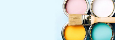 Four cans of paint with a paint brush resting on top of them. The paint colours are pint, white, yellow and blue.