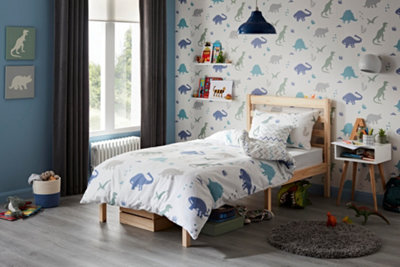 A children's bedroom decorated with dinosaur print wallpaper, bedding and wall art, and a selection of toys and books.