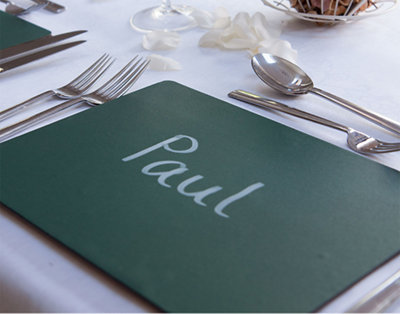 Placemat with the name 'Paul' written on it, placed on a white tablecloth with cutlery surrounding it.