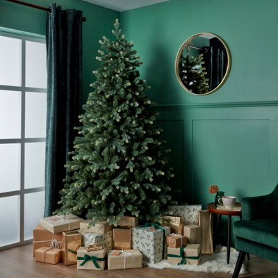 Artificial, natural effect tree in a room, with the skirt area surrounded by gifts.