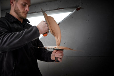 Person holding a plasterers hawk flat with one hand, and using the other hand to scoop up plaster using a plastering trowel.