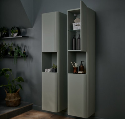 Two dark green tall bathroom storage cabinets installed next to each other in a dark green bathroom.