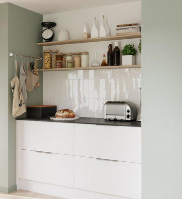 White and green kitchen with white tiled splashback and wooden open shelving.