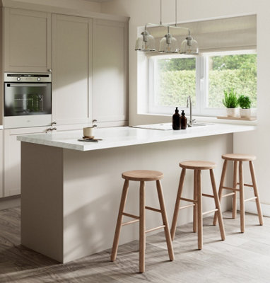 Cream kitchen with white marble effect worktops and a breakfast bar with wooden bar stools.