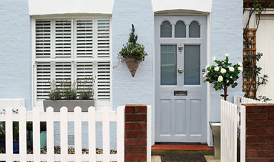 A house with a blue painted front door and light blue painted masonry walls, creating a bright and welcoming exterior.