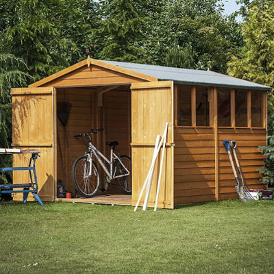 A large wooden shed with open doors and a bike inside the shed.