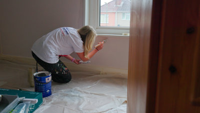 B&Q volunteer painting beneath a window sill.