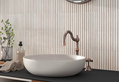 Minimal, beige fluted tiles behind a small sink basin unit.